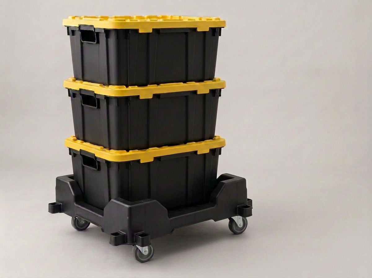 A stack of heavy-duty black 27-gallon moving bins with bright yellow lids beside a folding hand dolly